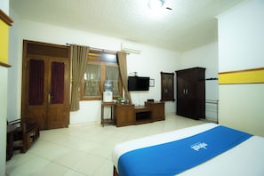 Un dormitorio con cama, escritorio, armario y televisor.