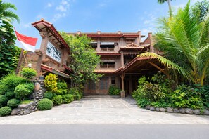 A traditional building with a stone entrance, a flag, and lush greenery. - Rehat at Pondok Betah (Bandung)