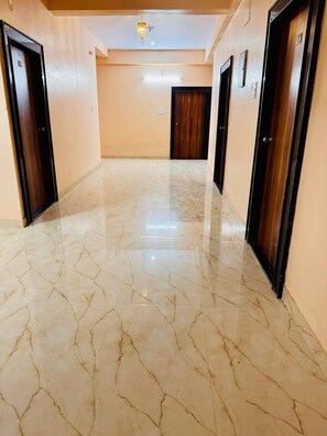 A hallway with marble flooring, wooden doors, and a ceiling light fixture.
