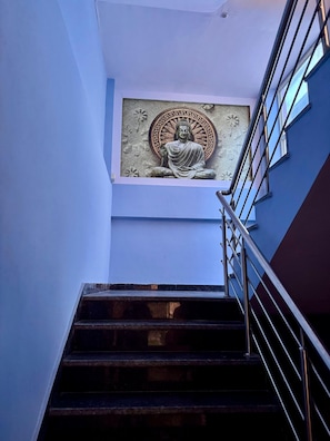Una escalera con barandilla de metal que lleva a un cuarto con una estatua de Buda en la pared.