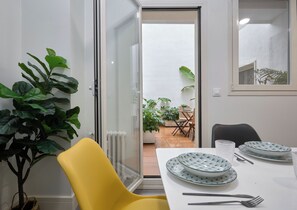 Ein Zimmer mit Esstisch für zwei Personen, einem gelben Stuhl und einem Blumentopf.