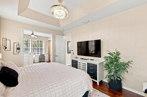 A bedroom with a large bed, a TV, a dresser, and a potted plant. - Villa American Dream — Luxury Waterfront Villa in Cape Coral with Gulf access (Cape Coral)