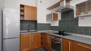 Una cucina con mobili in legno, un frigorifero in acciaio inossidabile, un fornello a gas e uno schienale piastrellato.