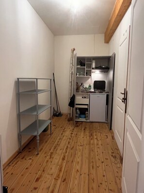 A compact kitchen with a built-in stove, a small sink, and a cabinet with shelves.