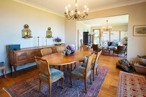 A dining area with a round wooden table, upholstered chairs, and a chandelier.