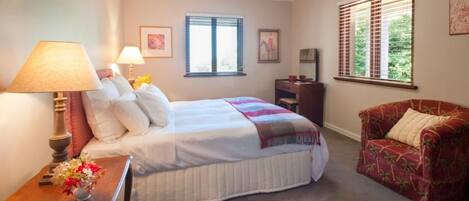 A bedroom with a bed, bedside tables, a chair, a desk, and a window.
