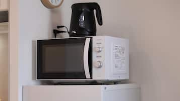 A white refrigerator with a microwave and a coffee maker on top.