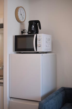 Un refrigerador blanco con un microondas y una cafetera encima.