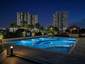 A swimming pool with a surrounding deck, palm trees, and high-rise buildings in the background. - Putra Majestik Manage By PP (Cheras)