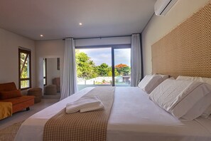 Una habitación de hotel con una cama grande, un sofá, una silla y vistas al exterior.