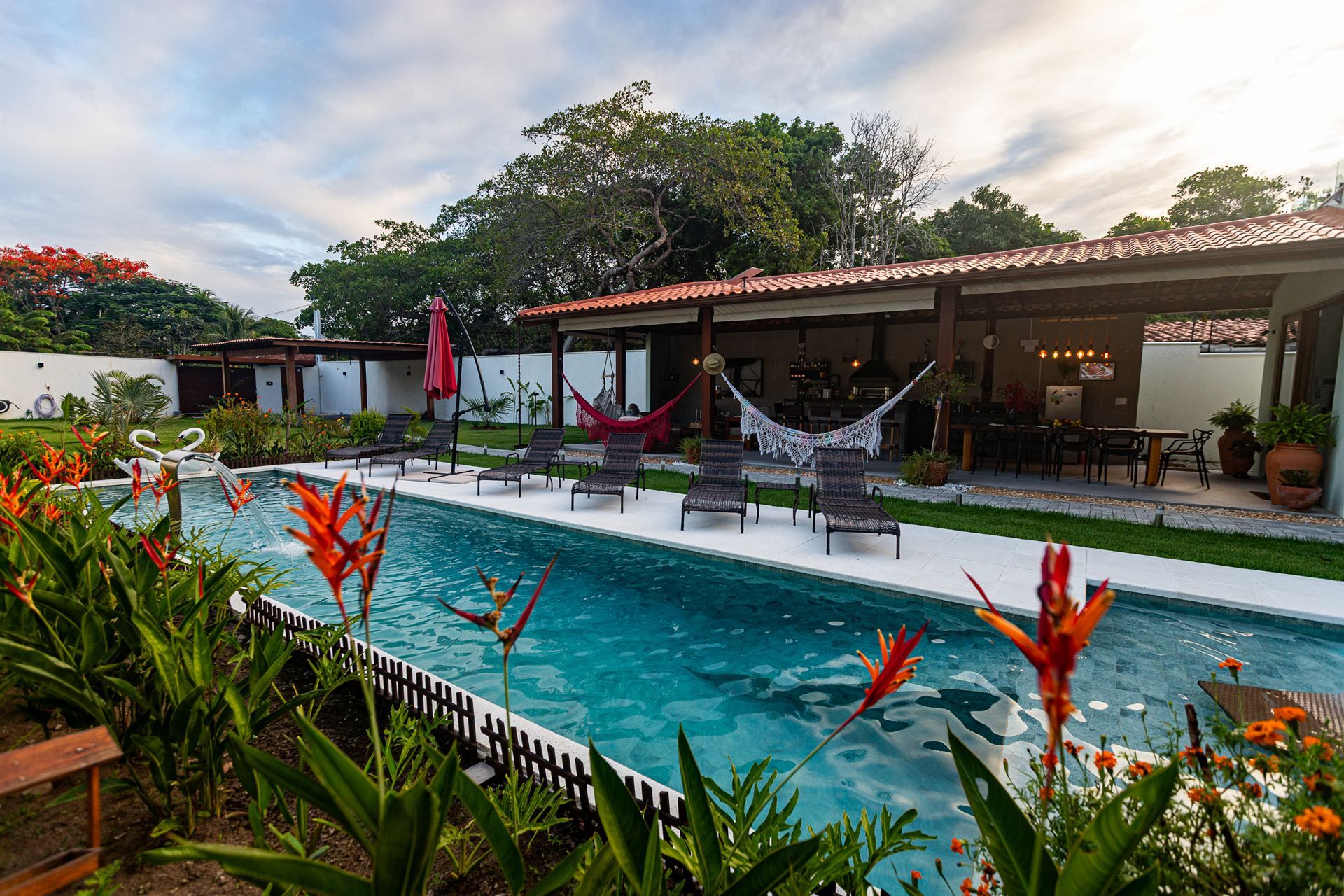 A swimming pool with lounge chairs and a covered patio area.