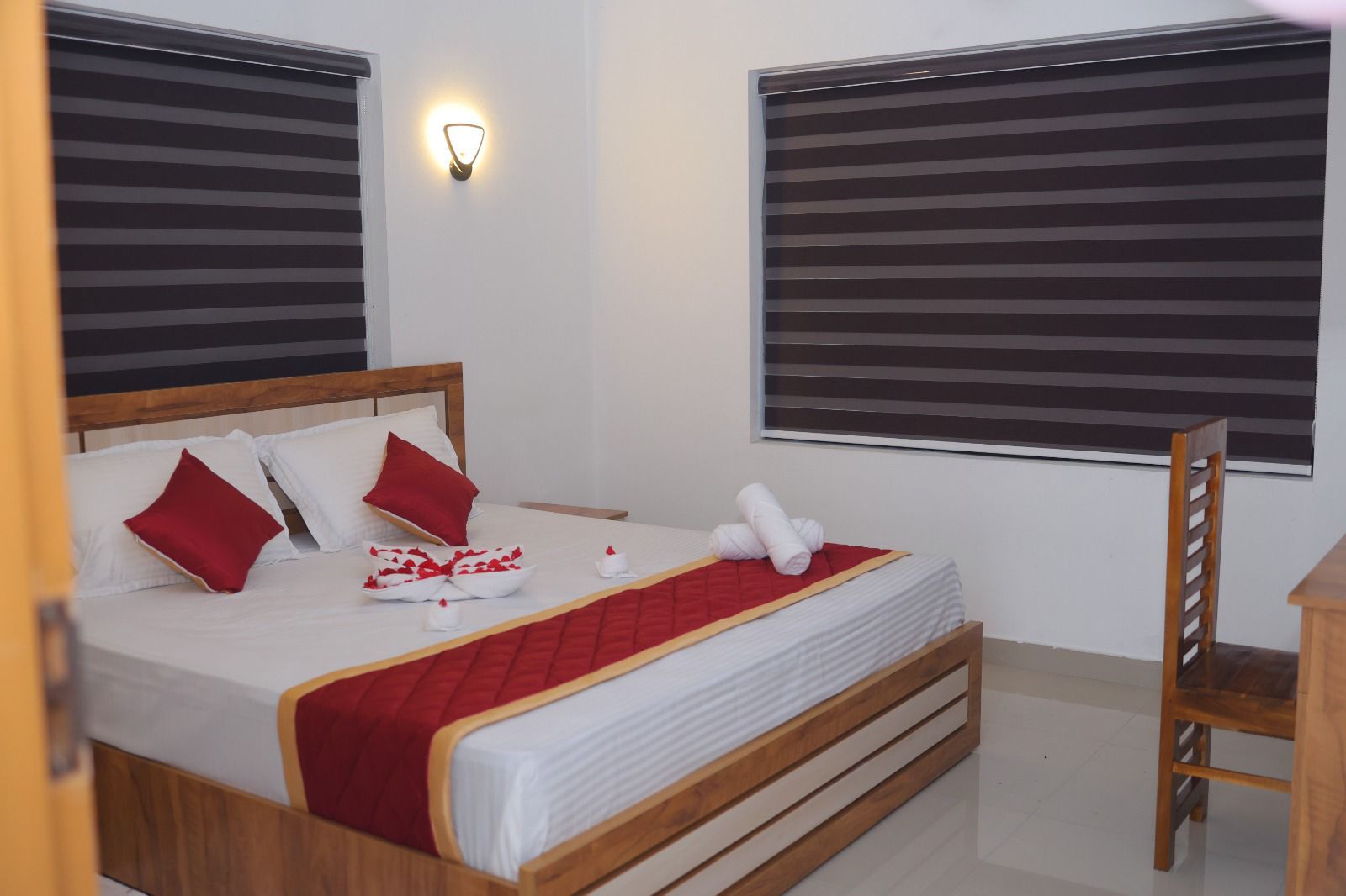 Una habitación de hotel con una cama, almohadas, una mesita de noche y una silla.