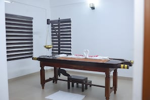 A room with a wooden table, a small stool, a bench, and a window with blinds. - Namasthe Wellness Hotel (Aluva)