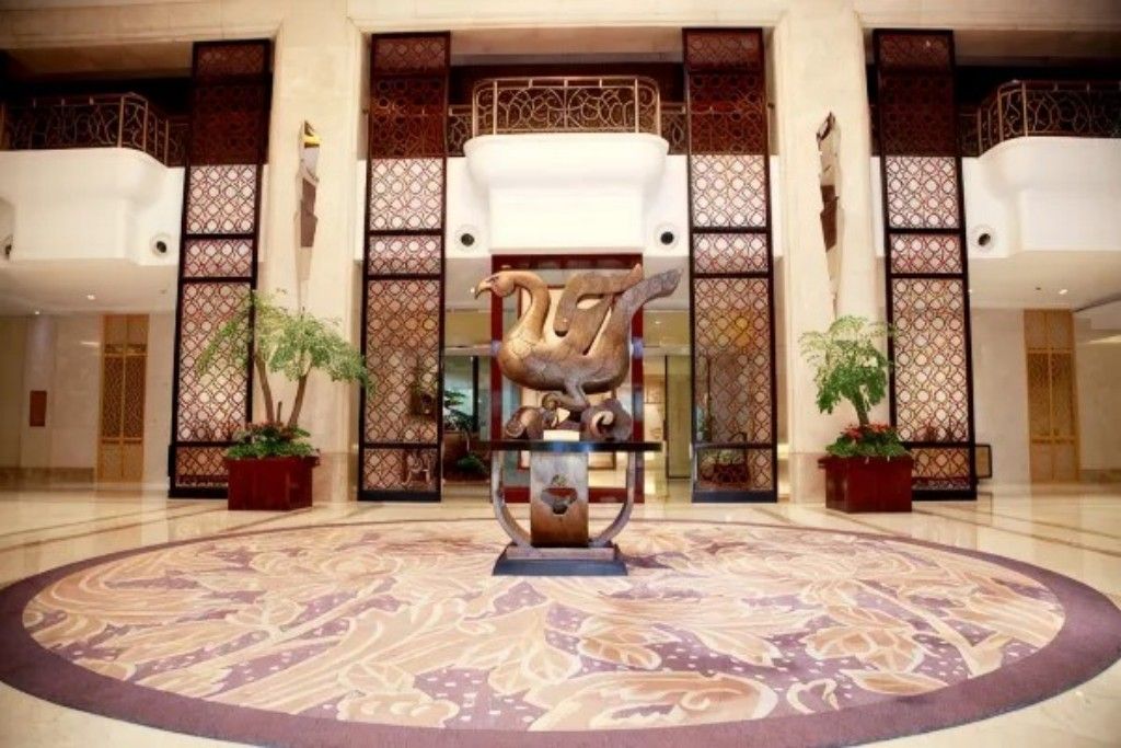 A lobby with a central sculpture, patterned floor, and decorative panels.