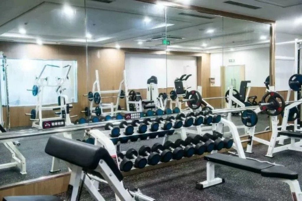 A gym with weightlifting equipment, benches, and mirrors.
