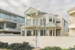 A multi-story residential building with a balcony and a covered porch. - Beachfront, Pool, Games Room, Sleeps 12 (Henley Beach)