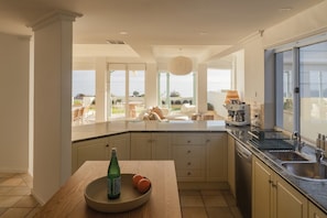Una cocina moderna con una isla grande, un comedor con vistas y un ventanal corredero al exterior.