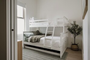 A bunk bed with a ladder, a bedside table, a potted plant, and a window. - Ilios | Luxury Apartment Steps from Henley Square (Henley Beach)
