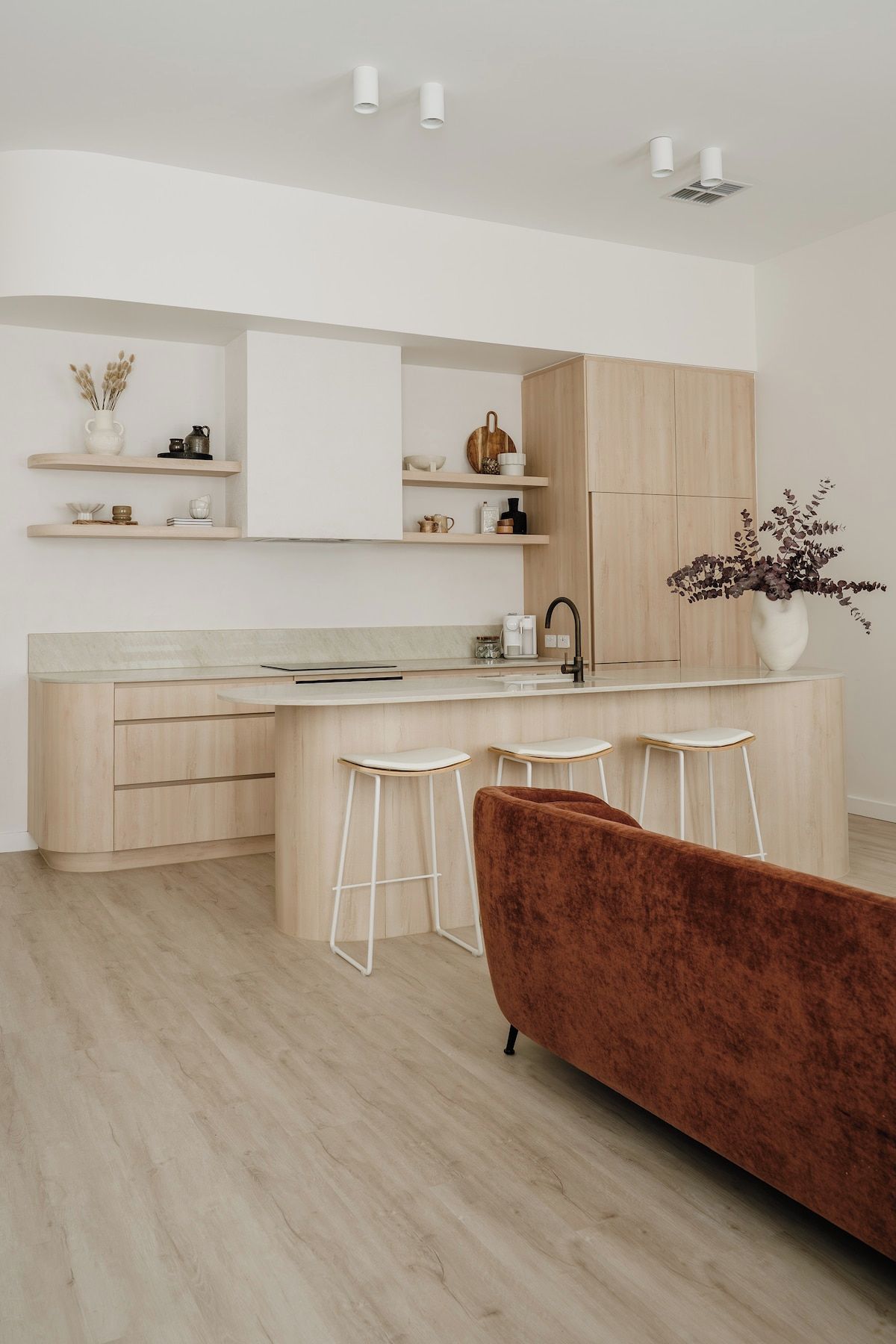 Une cuisine moderne avec des meubles en bois, un îlot central doté de tabourets et un coin bar.