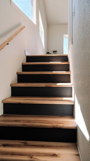 A staircase with wooden steps and a handrail, leading to an upper floor. - Hilltop Haus: Sweeping Mountain Views Above Denver (Morrison)