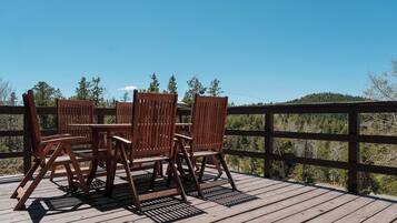 Une terrasse en bois avec une table et des chaises, donnant sur un paysage boisé.