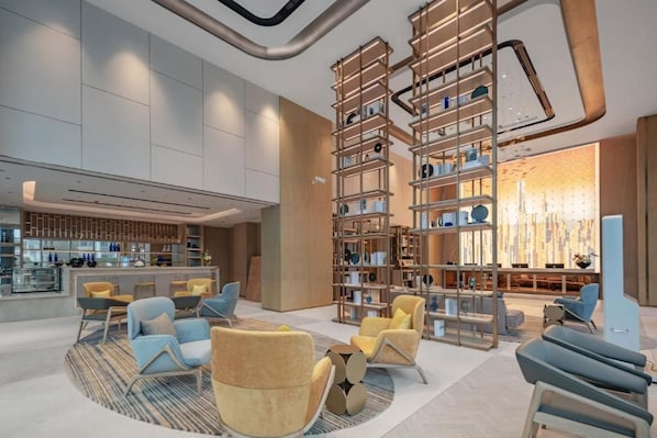 A modern lobby with seating areas, a bar, and a large bookshelf.