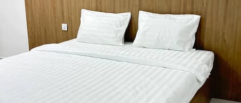 A bed with a wooden headboard, white bedding, and a marble floor.