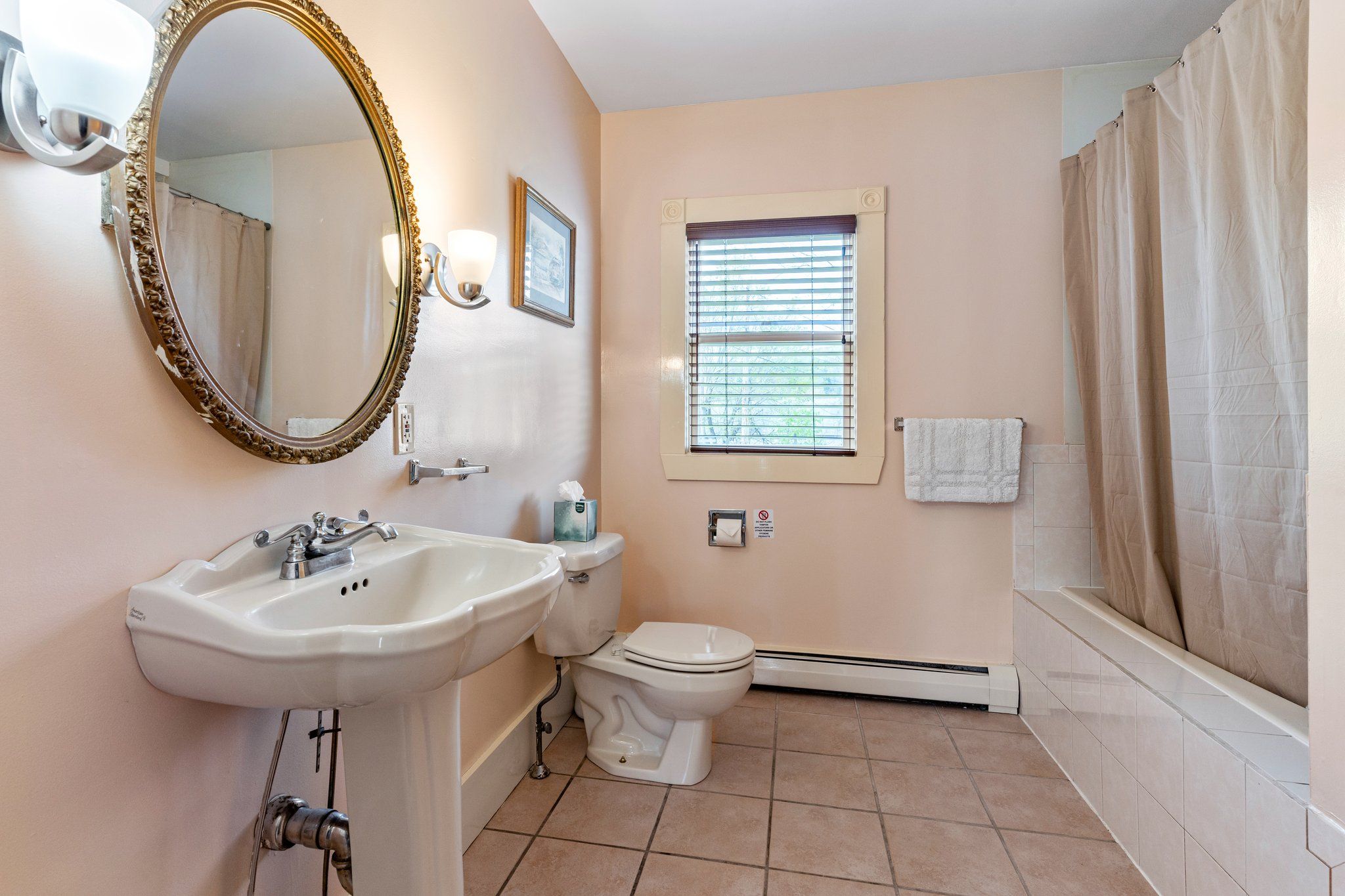 Een badkamer met een wastafel, toilet en een raam met zonwering.