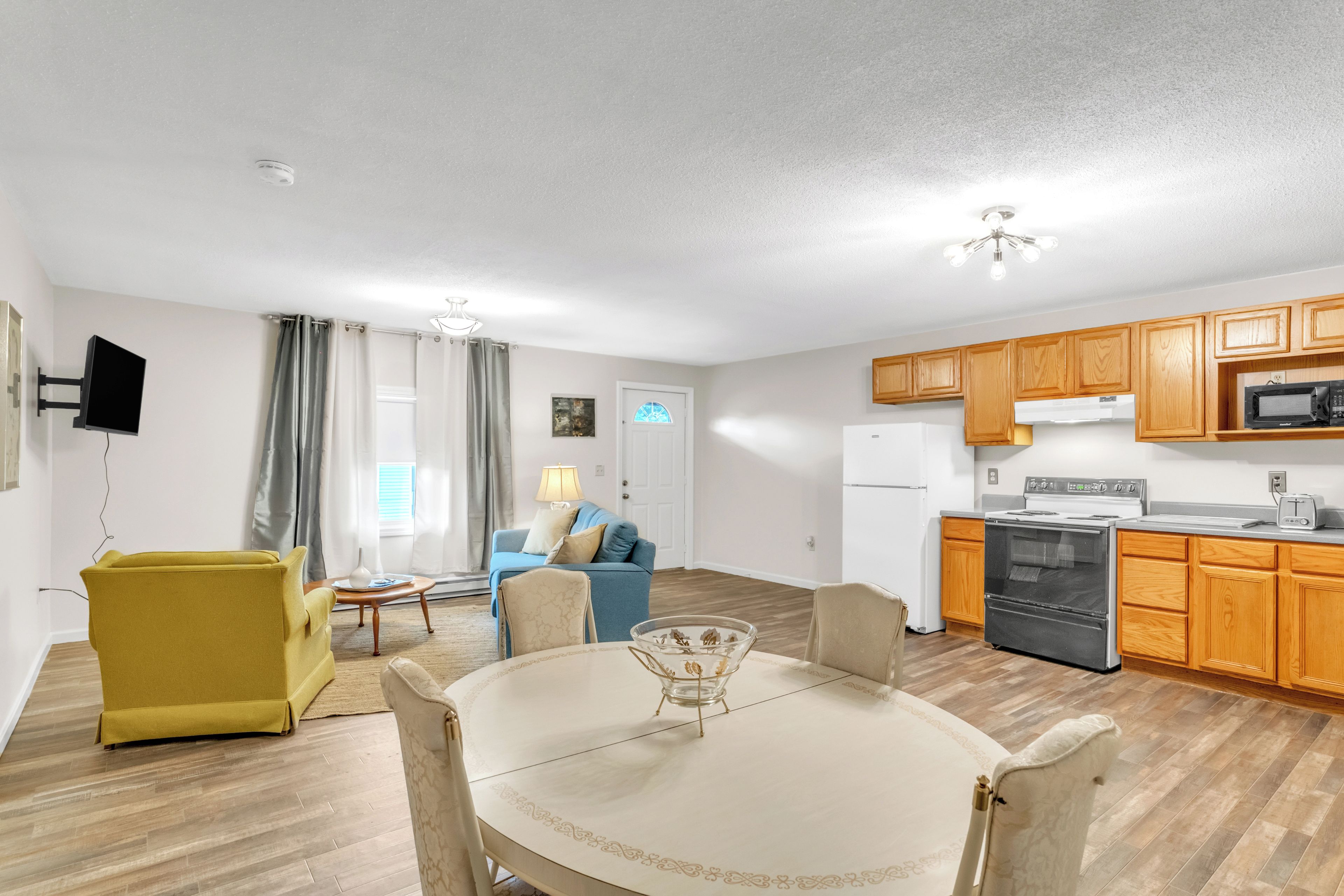 A compact living space with a dining area, a sofa, a television, and a kitchenette.