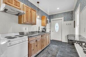 A kitchen with wooden cabinets, a white stove, and a patterned backsplash. - Trainmaster's Inn - Viking house first floor (Palmer)