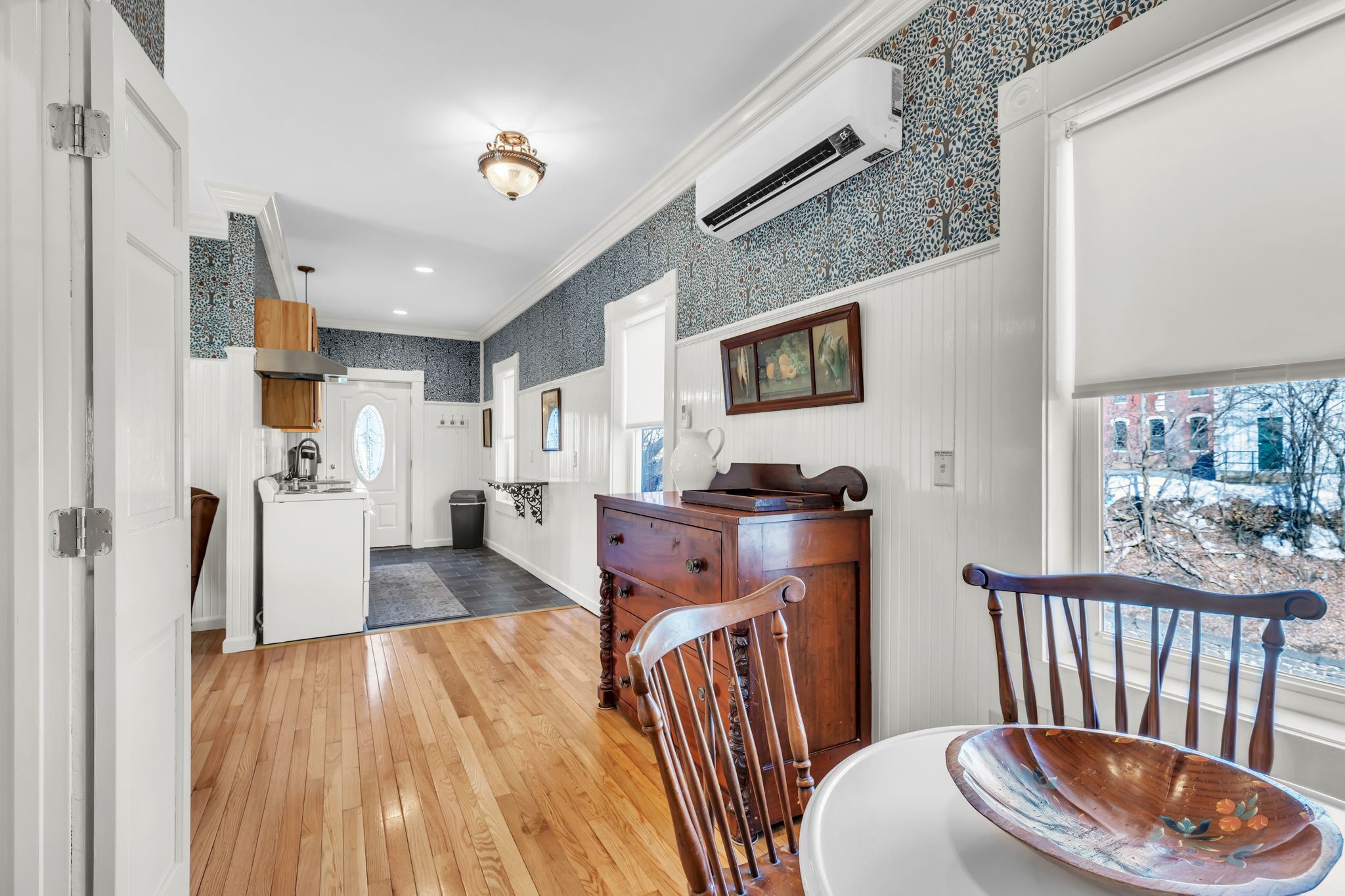 A kitchen with a wooden floor, white cabinetry, and a dining area with a table and chairs.