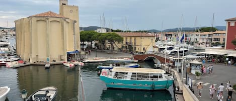 A marina with boats docked, a bridge, and buildings in the background.