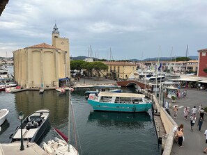 Ein Yachthafen mit vertäuten Booten, einer Brücke und Gebäuden im Hintergrund.