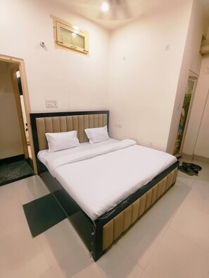 A single bed with a headboard, a small window, and a door leading to another room. - Kashi Gulab Homestay (Varanasi)