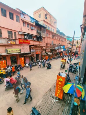 A busy street scene with pedestrians, vehicles, and commercial buildings. - Kashi Gulab Homestay (Varanasi)