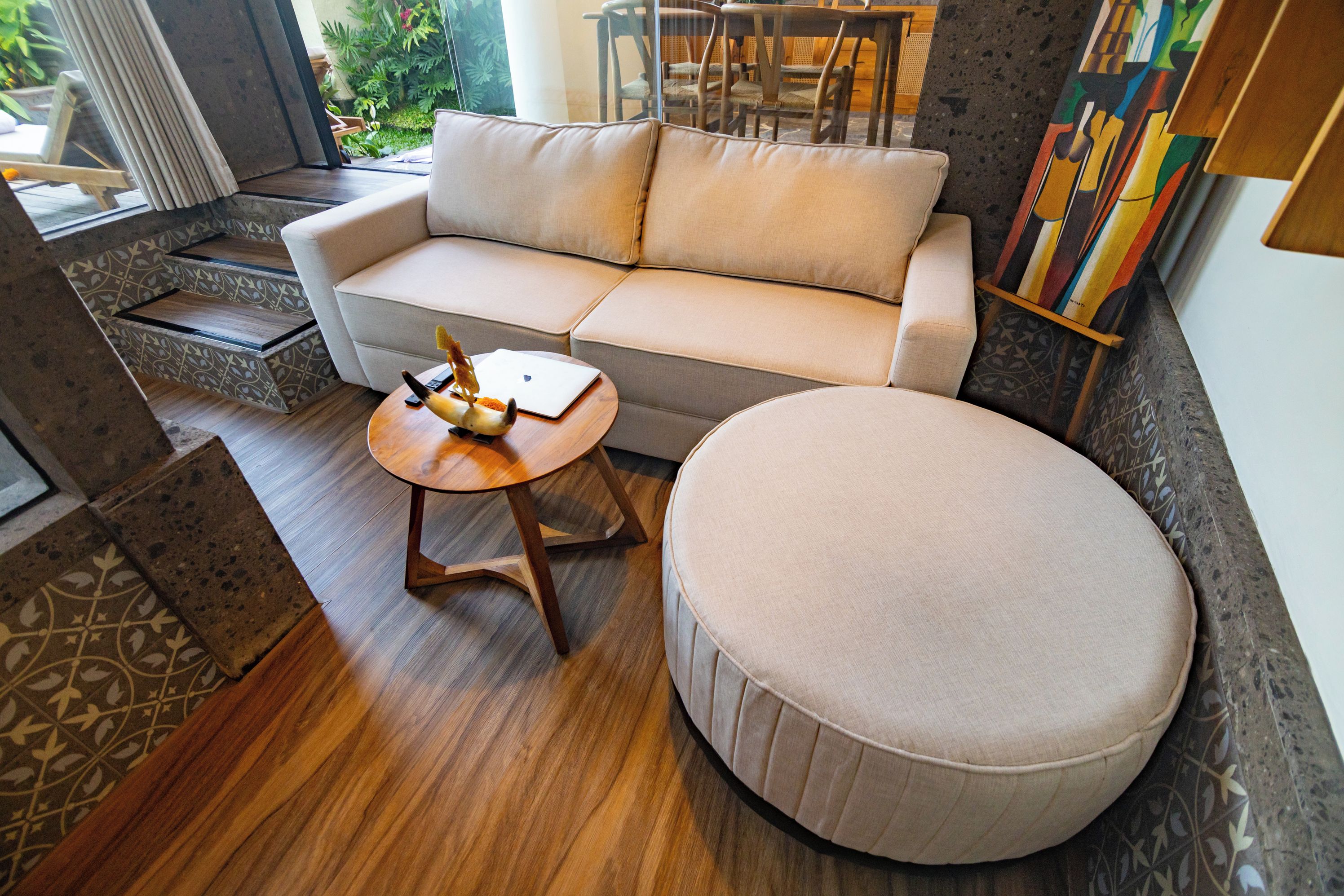 Ein stilvolles Wohnzimmer mit einer Couch, einem Hocker und einem runden Holztisch.