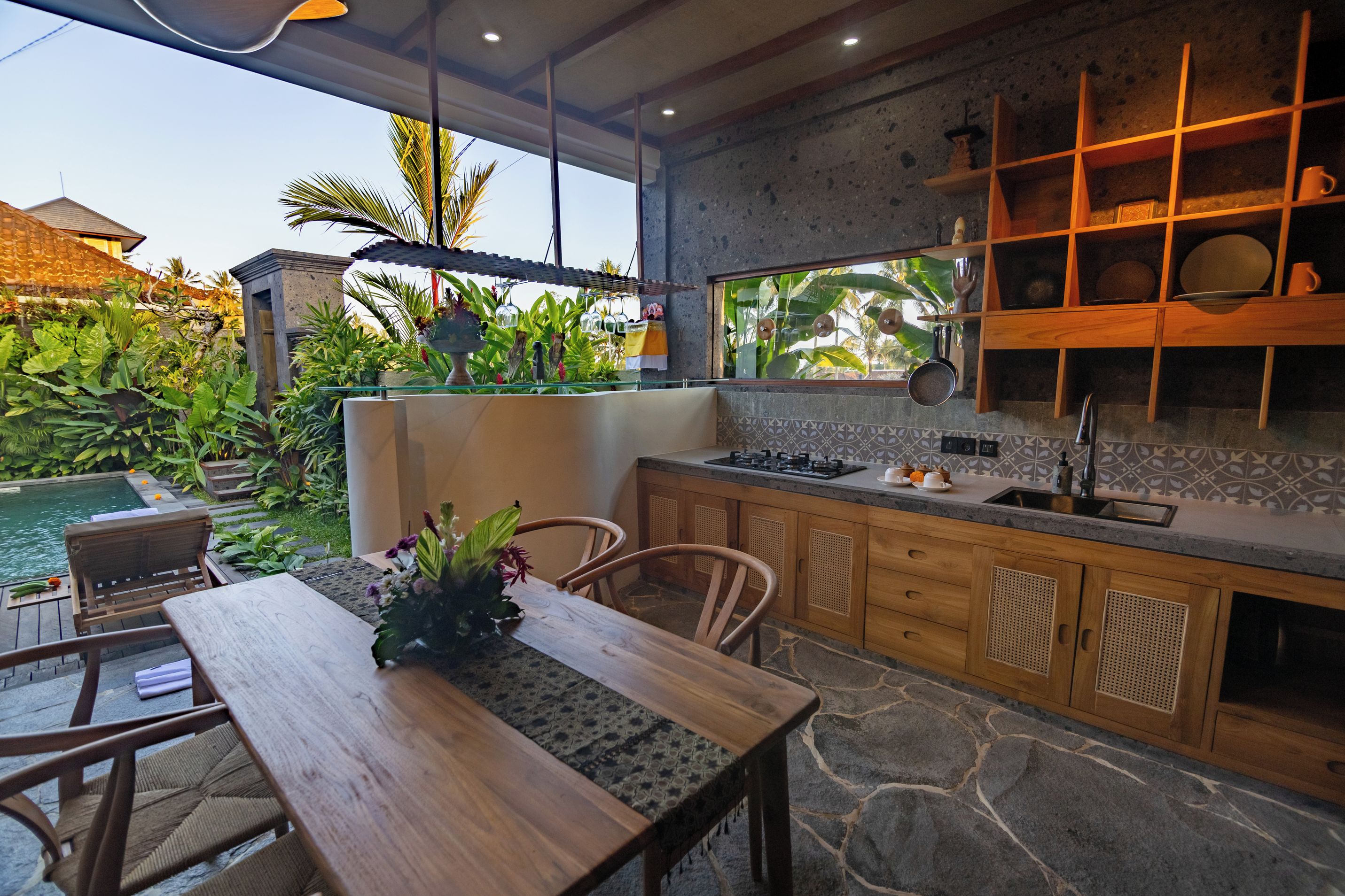 Una cocina moderna con encimera de piedra, armarios de madera y vistas a un jardín exuberante.