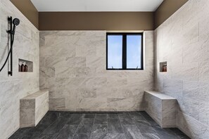 Une salle de bain moderne avec une douche, une fenêtre et des murs en marbre.