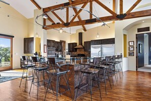 A spacious kitchen with high ceilings and exposed beams, featuring a central island with bar stools, modern appliances, and a stone backsplash. - Private Pool + Hot Tub + Snooker | 42-Acre Vineyard | The Villa at Ambyth Estate (Templeton)