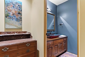 A bathroom with a marble vanity, a sink with a red basin, a mirror with a decorative frame, and a painting on the wall. - Private Pool + Hot Tub + Snooker | 42-Acre Vineyard | The Villa at Ambyth Estate (Templeton)