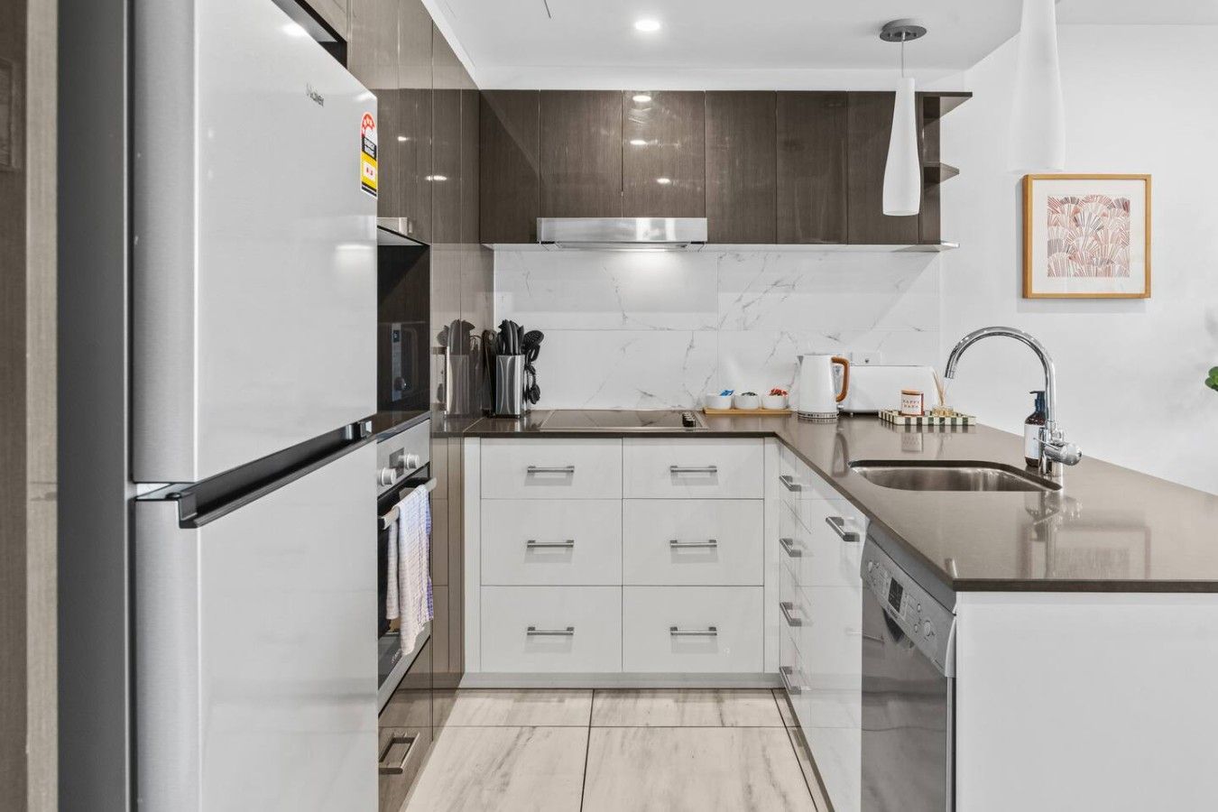 A modern kitchen with a stainless steel refrigerator, a built-in oven, a microwave, and a sink with a faucet.