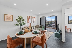 Una sala moderna con comedor, un juego de sofá, una mesa de centro y un amplio ventanal con vistas al exterior.