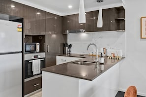 Una cocina moderna con una isla central, electrodomésticos de acero inoxidable y un microondas.
