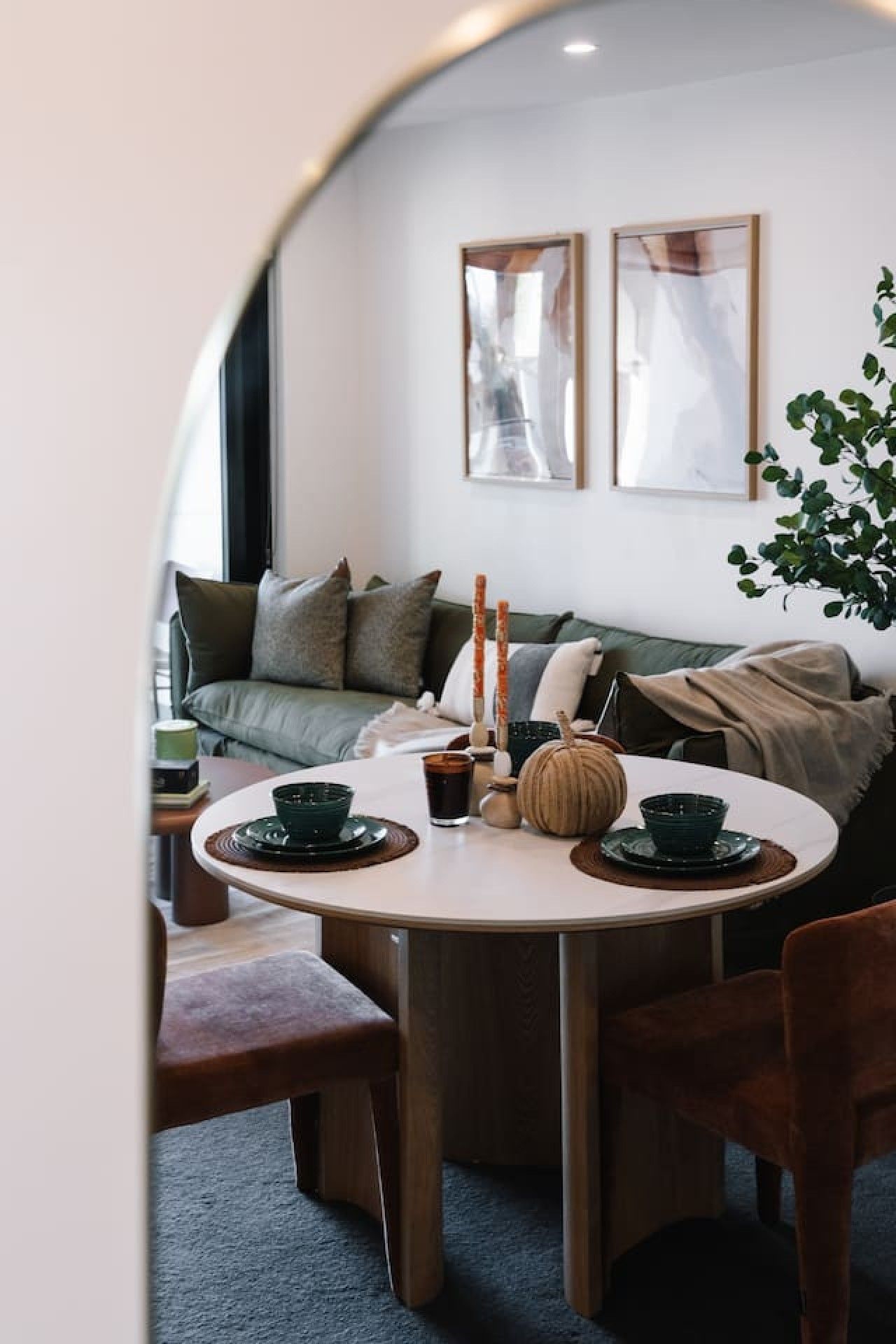 A cozy dining area with a round table, chairs, and a sofa in the background.