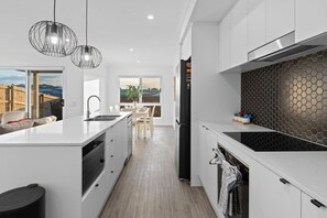 A modern kitchen with a central island, pendant lighting, and a view to the outside. - Brand New4BR Home |Aircon Every Bedroom |GoodValue (White Rock)
