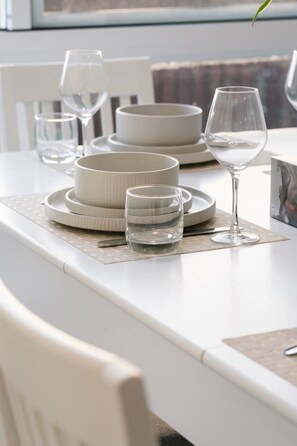 A dining table set with plates, bowls, glasses, and a wine glass. - Brand New4BR Home |Aircon Every Bedroom |GoodValue (White Rock)