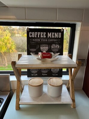 Um letreiro de menu de café com diversas opções de café e uma embalagem de biscotti sobre uma mesa.