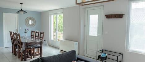Un salon moderne comprenant un coin repas, un canapé gris, une table à manger en bois et un luminaire suspendu au plafond.