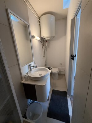 Et moderne badeværelse med vask, toilet og spejl.