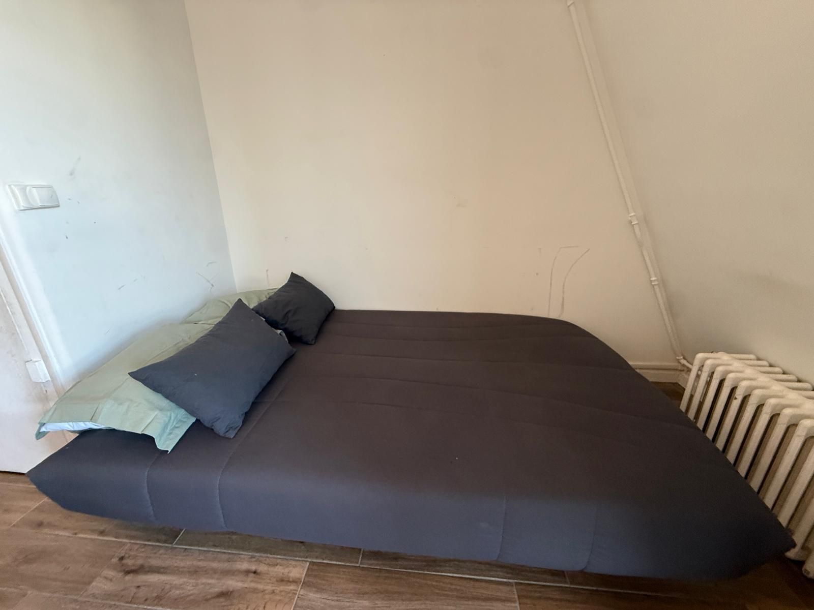 Et værelse med en seng, en radiator og en stikkontakt.